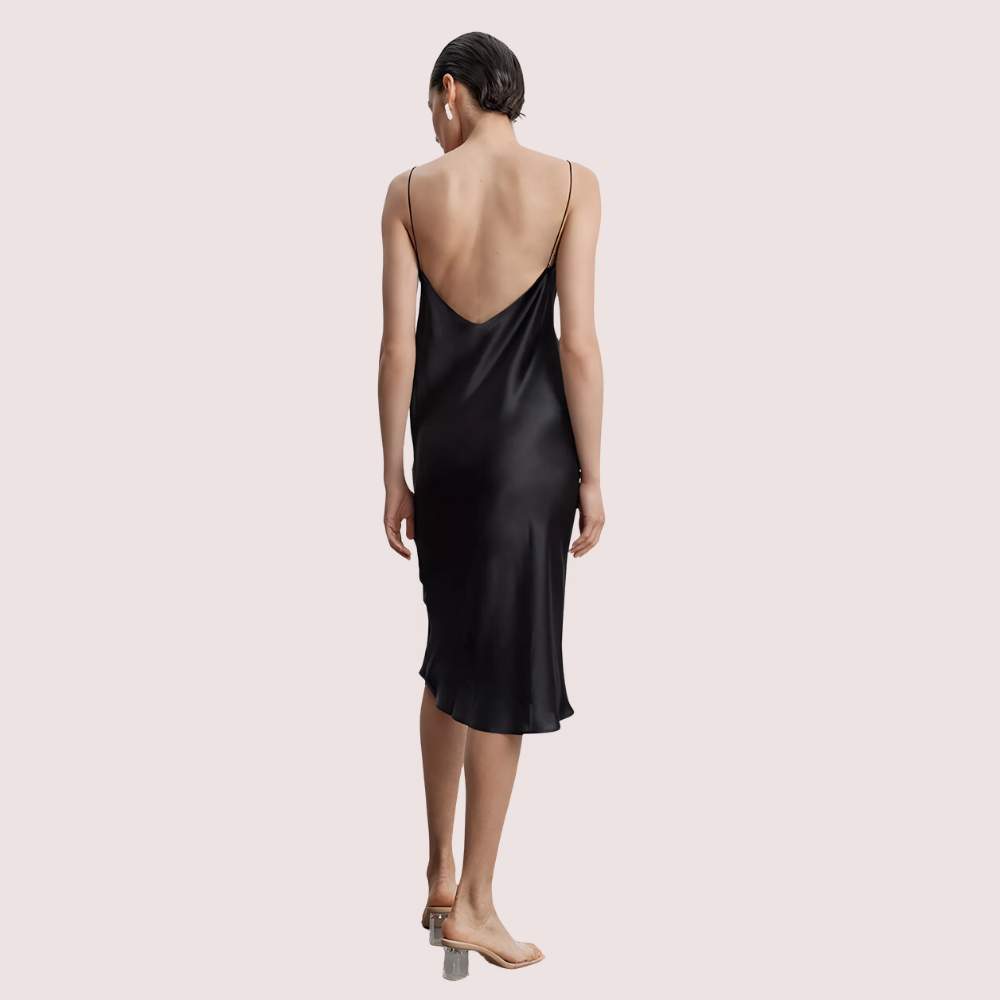 Woman wearing a black slip dress on a light pink background