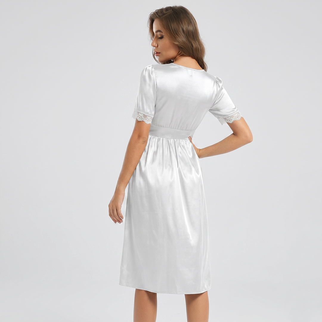 Woman wearing a white dress with lace details on a plain background