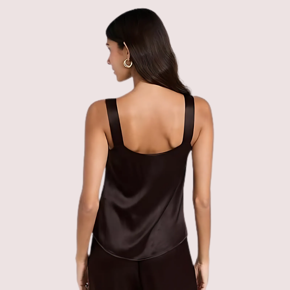 Woman wearing a black satin tank top against a light pink background
