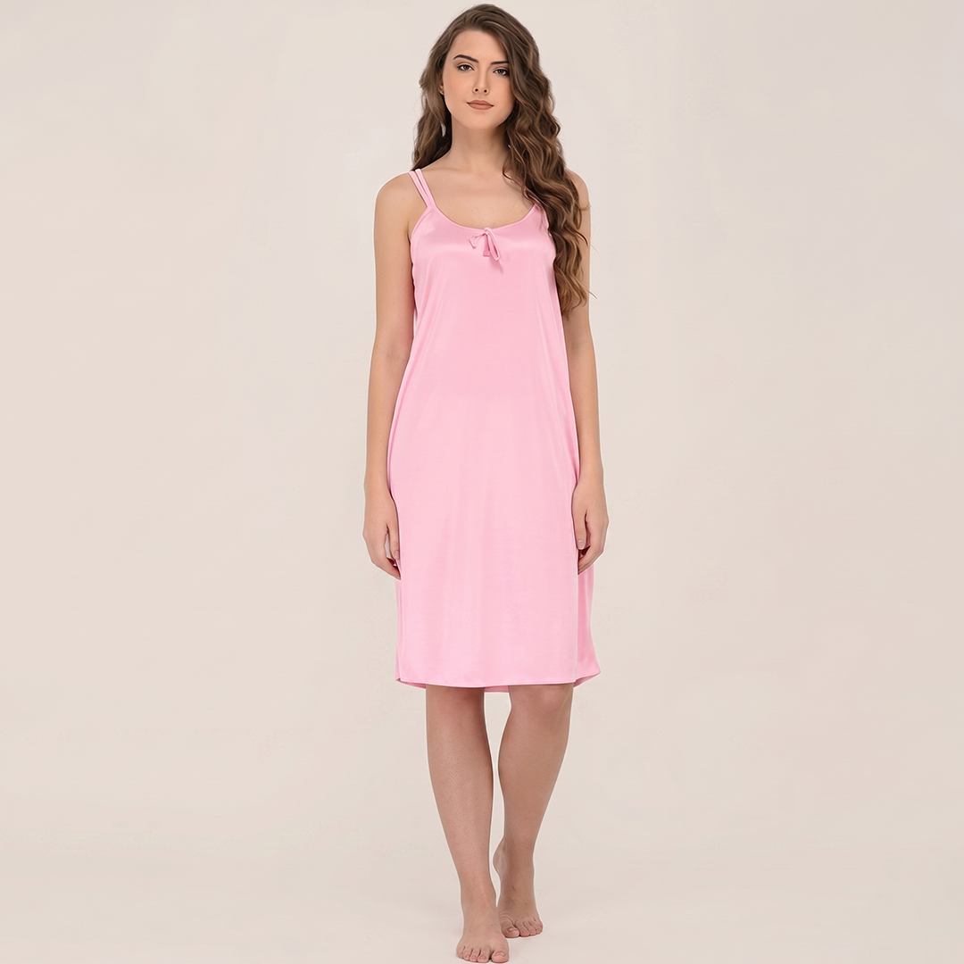 Woman wearing a pink slip dress against a beige background