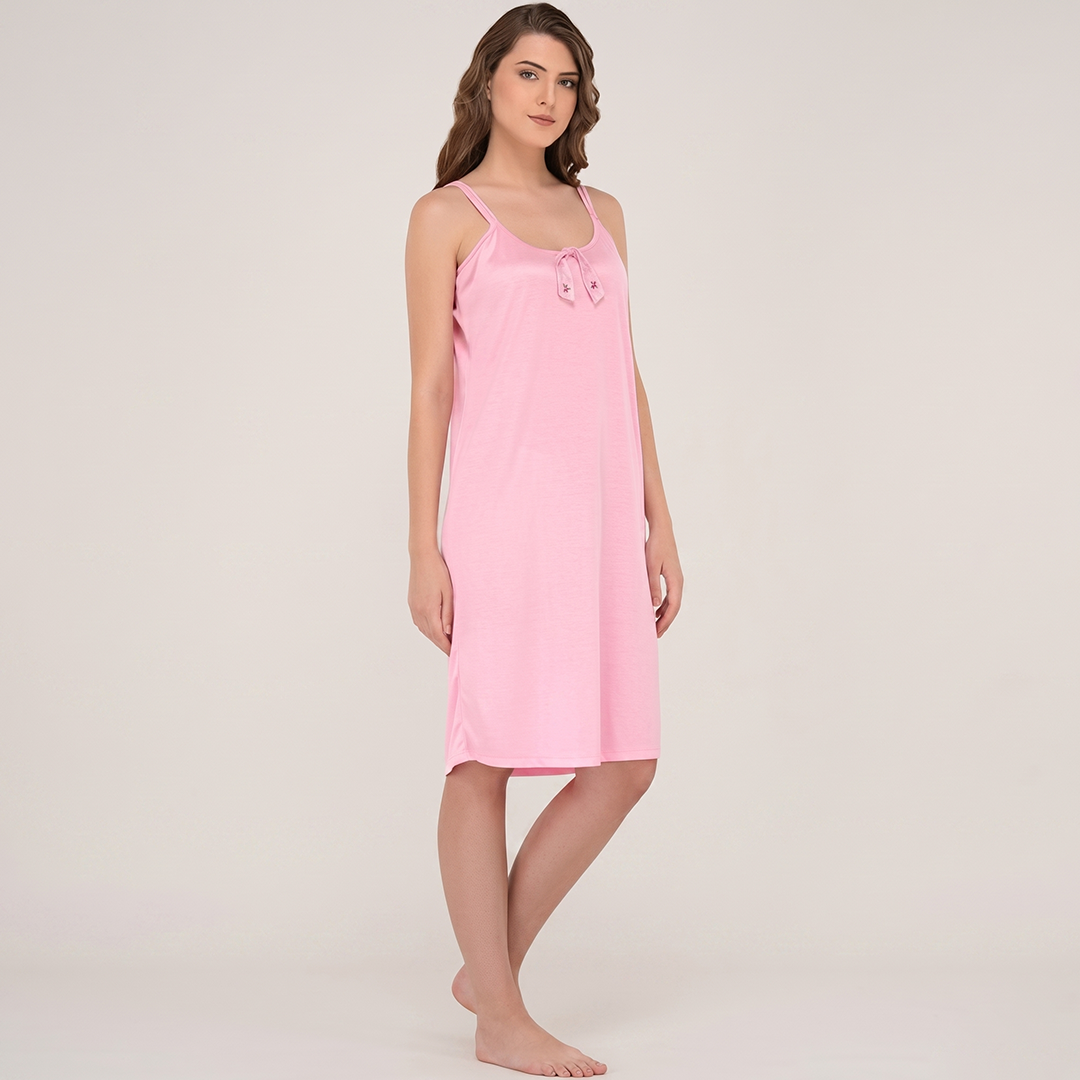 Woman wearing a pink slip dress against a plain background
