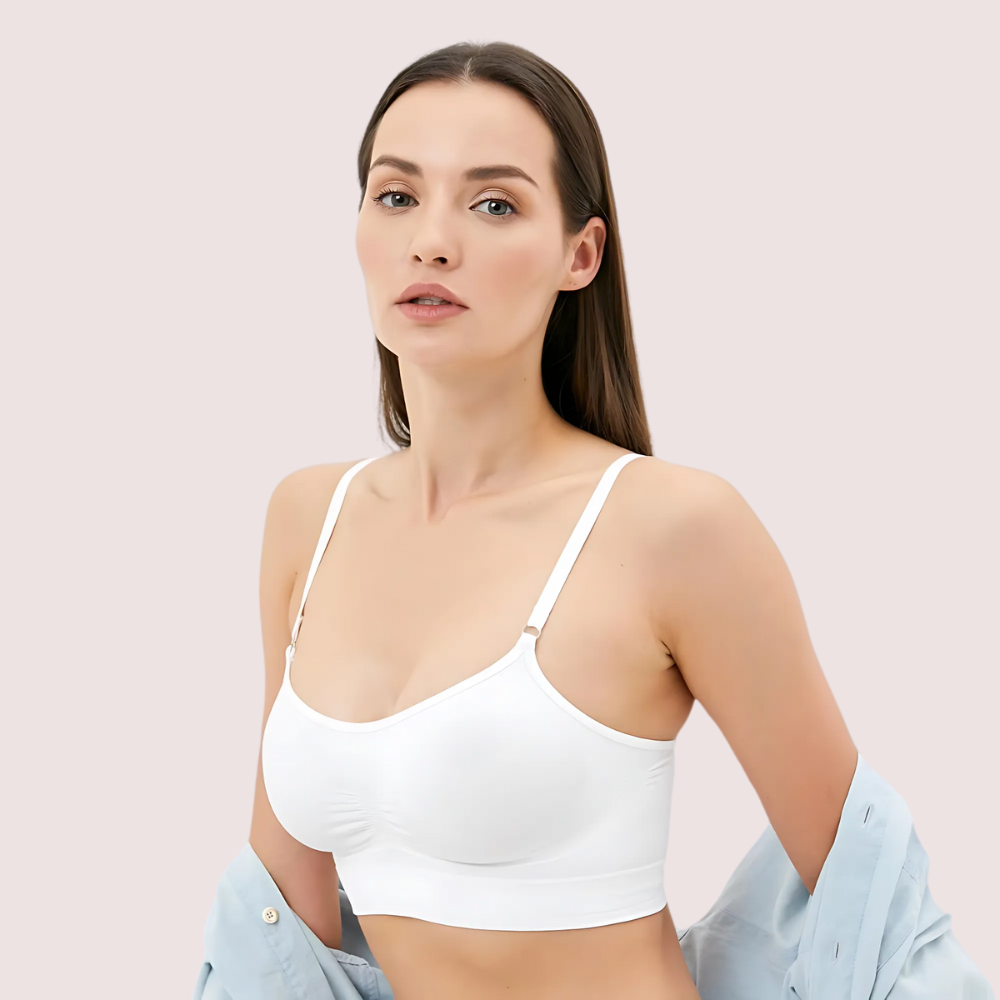 Woman wearing a white bralette against a light pink background