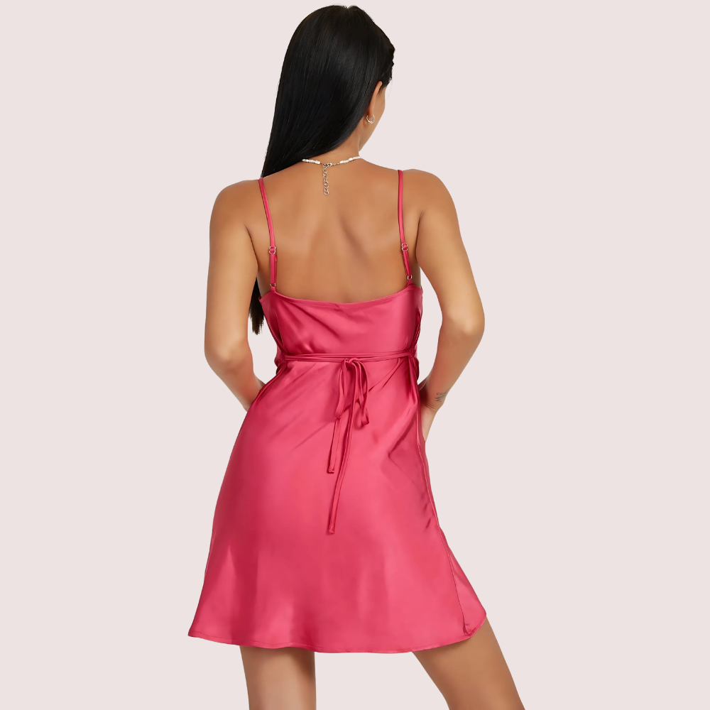 Pink satin dress worn by a model on a light pink background