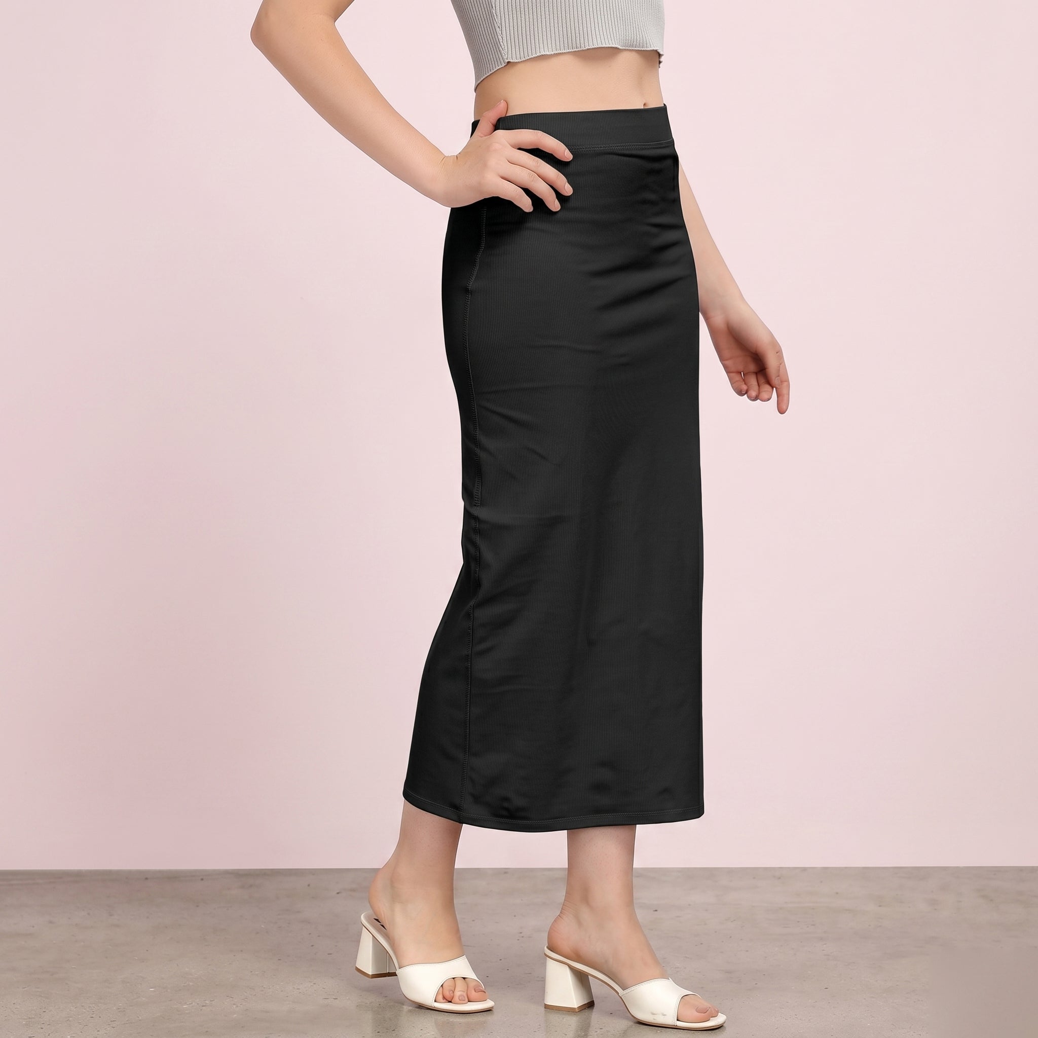 Person wearing a black skirt with a plain background