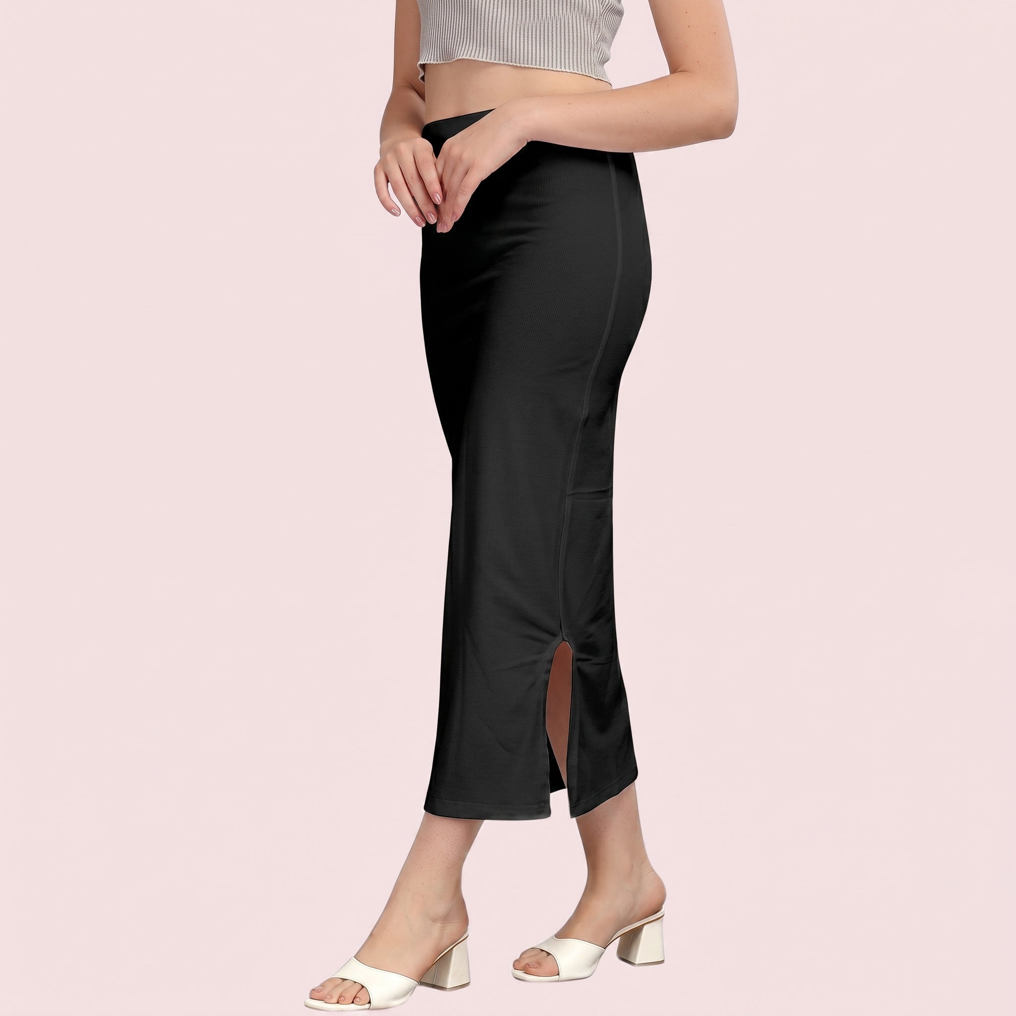 Person wearing black pants with a side slit on a pink background