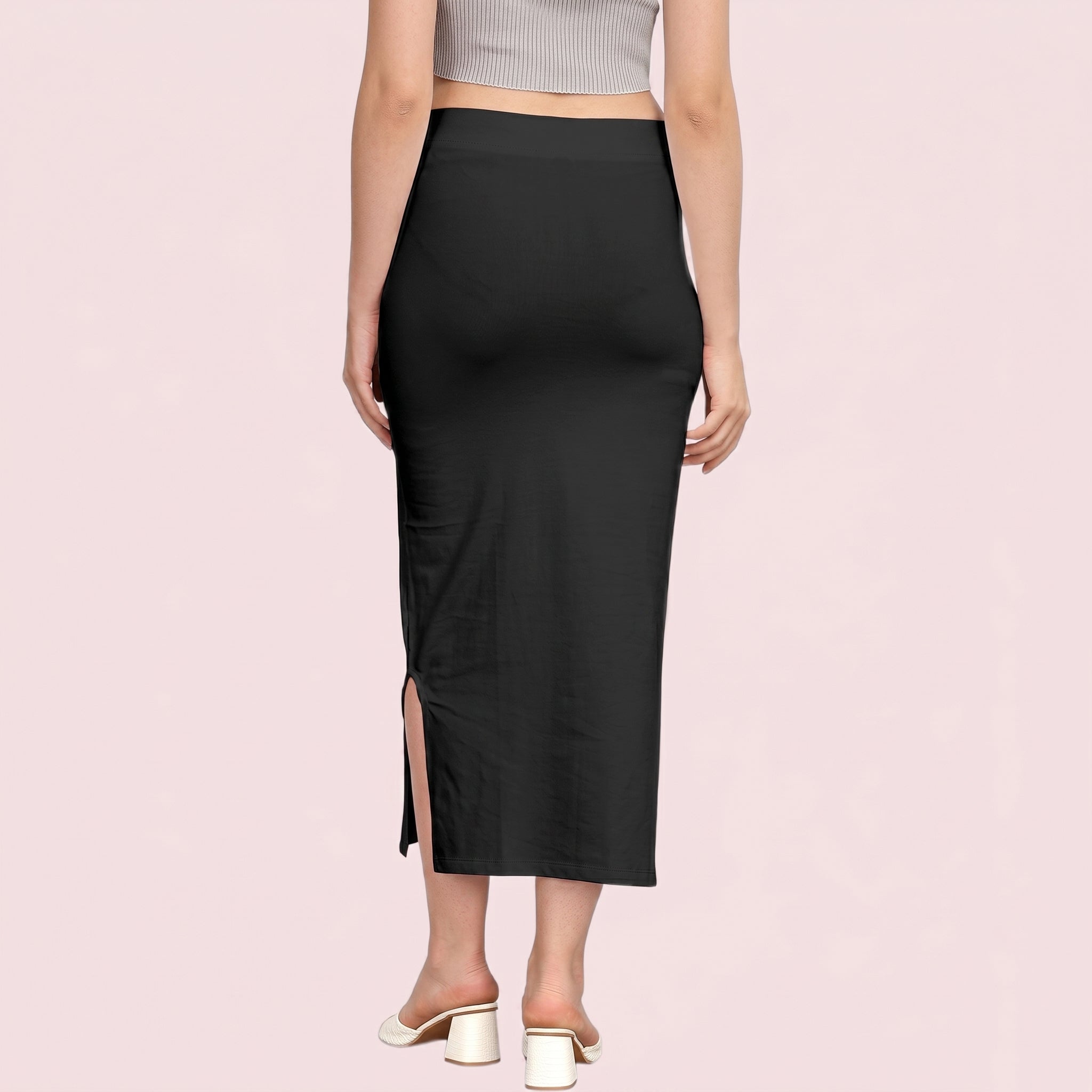Person wearing a black skirt with a side slit on a pink background