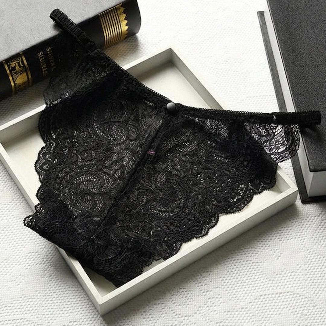 Black lace lingerie set on a white surface with books in the background