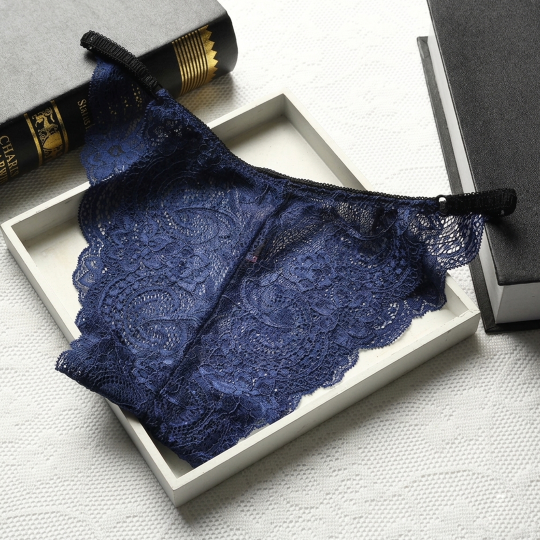 Blue lace underwear in a white box on a textured surface with books in the background.