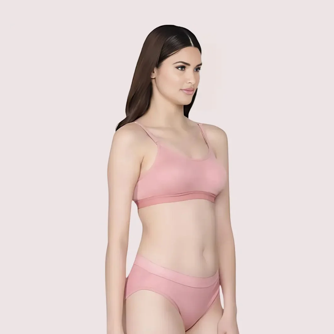 Woman wearing a pink bra and panties set on a light pink background