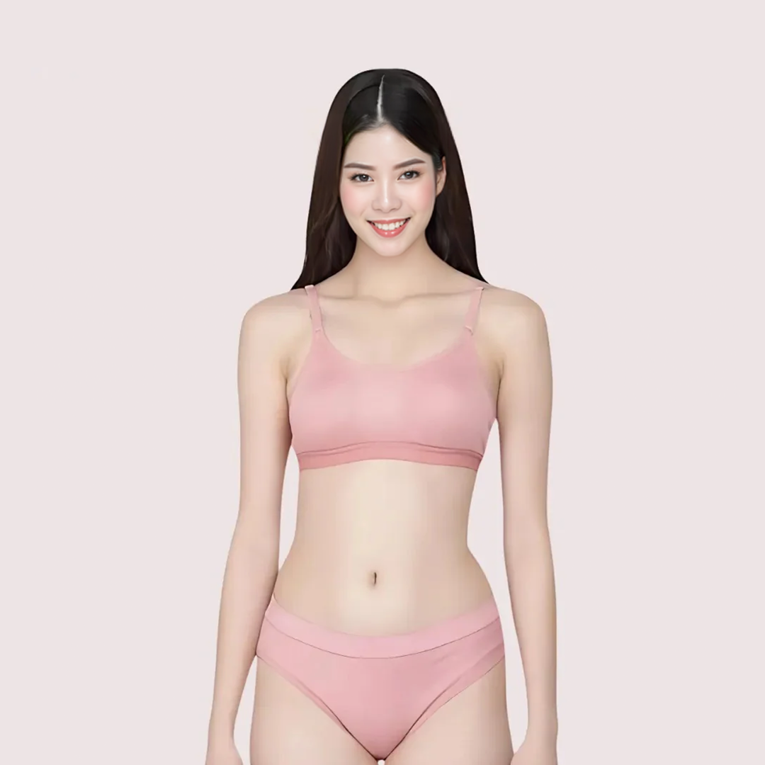 Woman wearing a pink bra and panties set on a light pink background