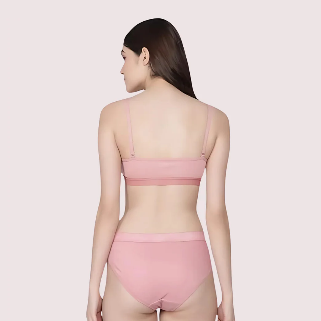 Woman wearing a pink bra and panties set on a light pink background