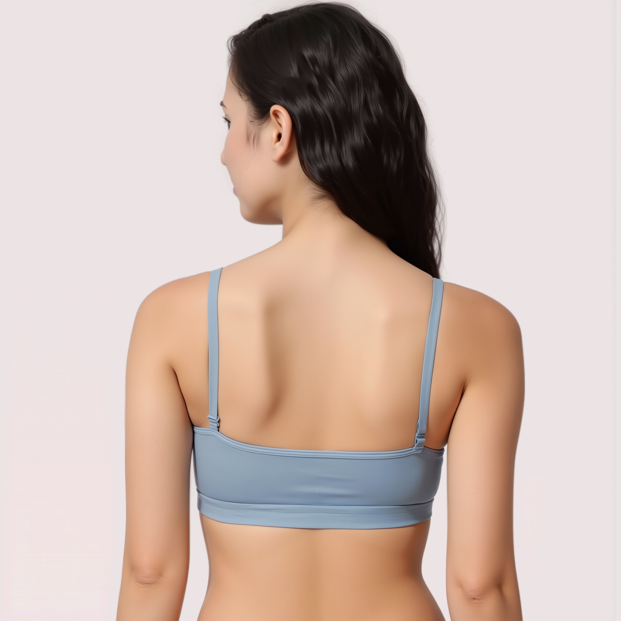Woman wearing a light blue bralette on a plain background