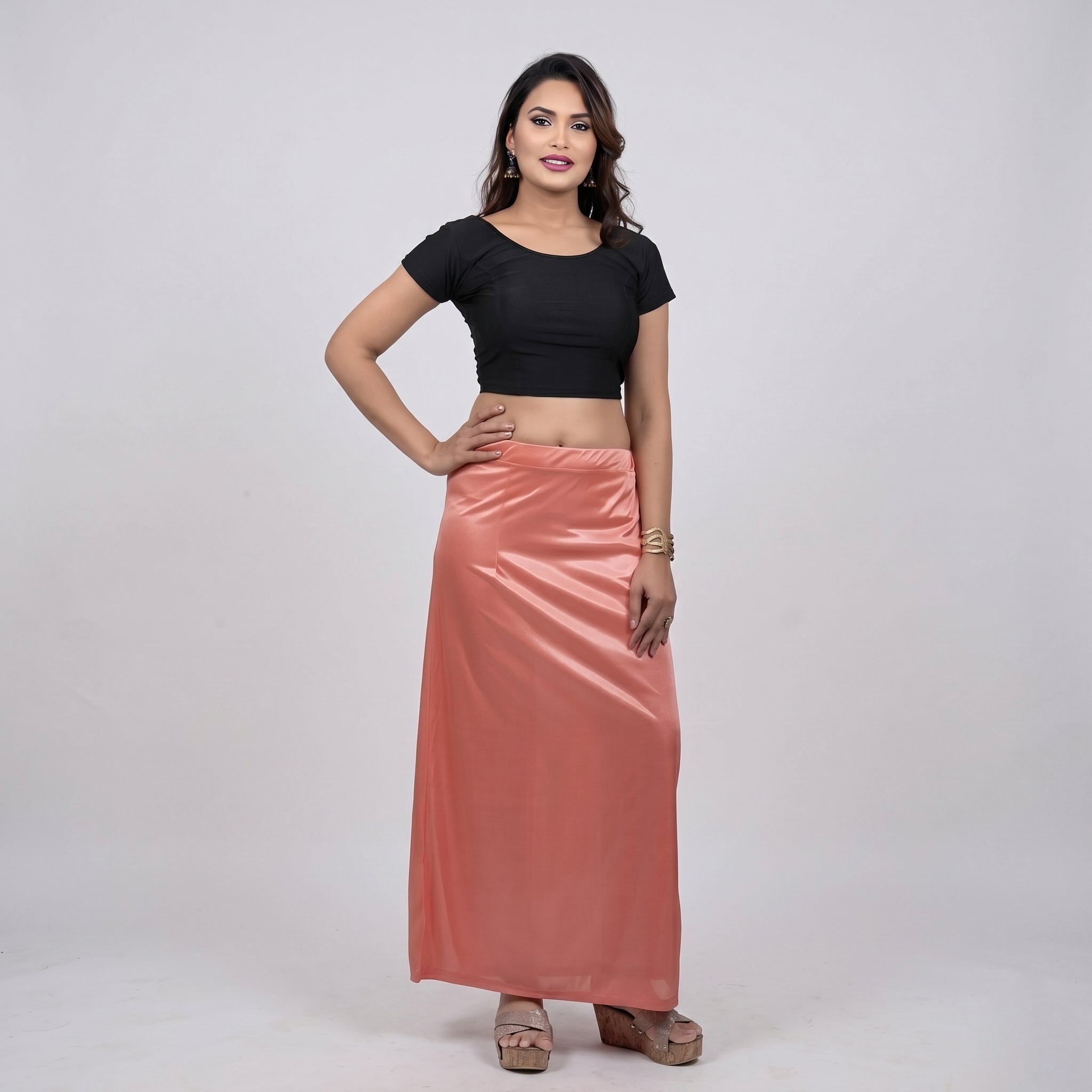Woman wearing a black top and pink skirt on a white background