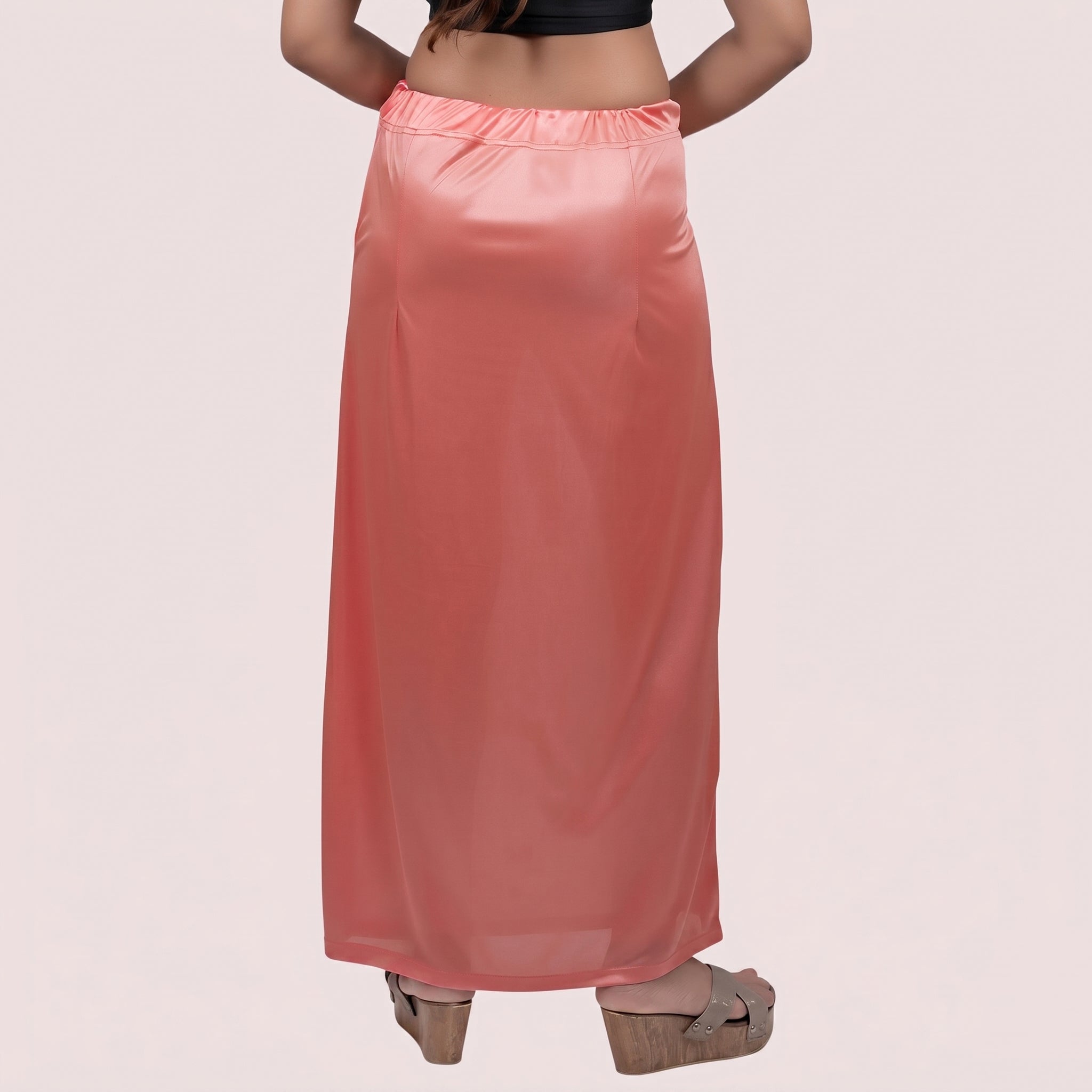 Person wearing a long pink satin skirt on a light pink background